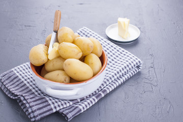 Young boiled potatoes with butter in a cup. Towel and gray background. Delicious vitamin summer dinner. Copy space.