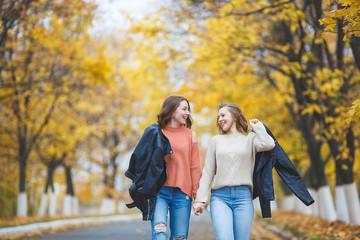 Naklejka na ściany i meble Young pretty girls having fun outdoors in autumn background. Cheerful friends in the fall time