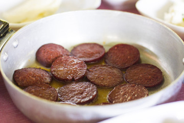 Turkish breakfast. Fried sausage in a small frying pan on the table