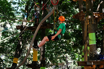 Man in safety equipment  on rope descent. Leisure time in rope park.