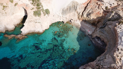 Fototapeta na wymiar Aerial drone bird's eye view of iconic volcanic white chalk beach and caves of Tsigrado with turquoise and sapphire clear waters, Milos island, Cyclades, Greece