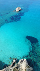 Aerial drone bird's eye view of iconic volcanic white chalk beach and caves of Tsigrado with turquoise and sapphire clear waters, Milos island, Cyclades, Greece