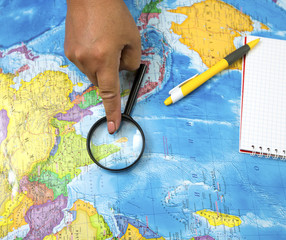Fototapeta na wymiar Search for new bright places to travel on the map and looking at the magnifying glass