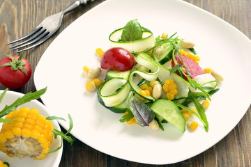 Fresh salad with zucchini, arugula, corn, cucumbers and tomatoes