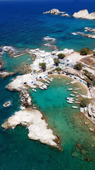 Aerial drone bird's eye view photo of picturesque small fishing harbor of Mandrakia with boat houses called syrmata and fishing boats docked on turquoise clear waters, Milos island, Cyclades, Greece
