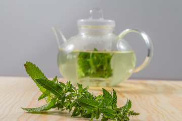 Teapot filled with pepermint tea on a wooden table