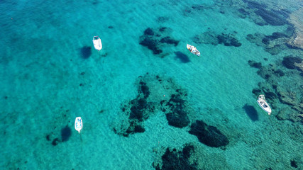 Aerial drone bird's eye view photo of traditional fishing boat docked in port of Polonia with turquoise clear water sea, Milos island, Cyclades, Greece