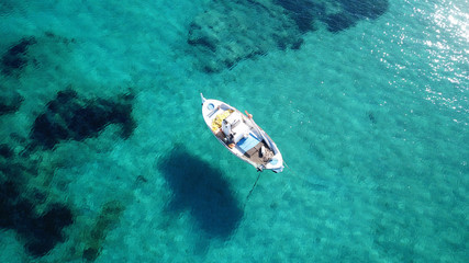 Fototapeta na wymiar Aerial drone bird's eye view photo of traditional fishing boat docked in port of Polonia with turquoise clear water sea, Milos island, Cyclades, Greece