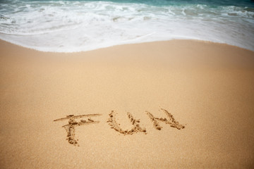 Fototapeta na wymiar Word FUN in sand of beach