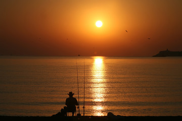 Fisherman's silhouette at sea shore early in the morning