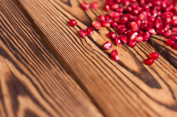 Heap of fresh ripe red seeds of pomegranate on old brown weathered wooden planks