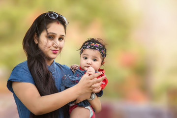 Closeup of happy mother and daughter standing in the park looking at camera. selective focus, shallow depth of field.