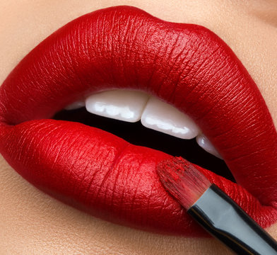 Macro and close-up creative make-up theme: beautiful female lips with red lipstick and brush