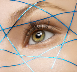 Macro and close-up creative make-up theme: beautiful female eyes with blue lines