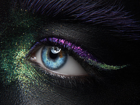 Macro And Close-up Creative Make-up Theme: Beautiful Female Eyes With Black Skin With Green And Purple Pigment And Sparkles