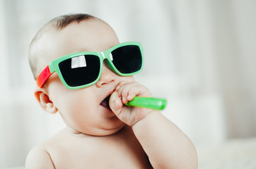 Funny baby in sunglasses with spoon