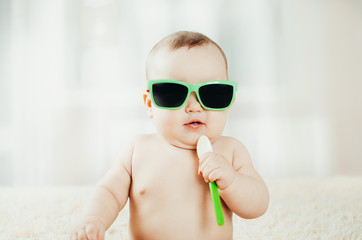 Funny baby in sunglasses with spoon