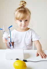 Little girl in a mask for inhalations, making inhalation with nebulizer at home inhaler on the table, indoor, sick child