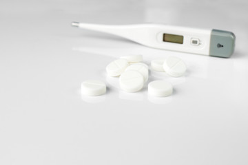 White pills and thermometer. The concept of medicine, disease, health.