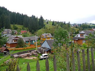 Private houses with private plots on the green mountain slope against the background of a cloudy sky