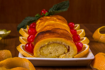 Rocambole de laranja no prato branco no fundo de madeira