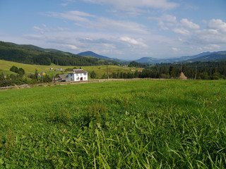 a magnificent green glade of grass leading to houses in the distance