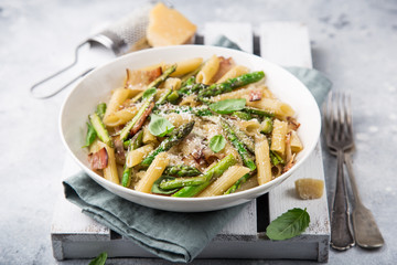 asparagus and bacon penne pasta with parmesan cheese in white bowl