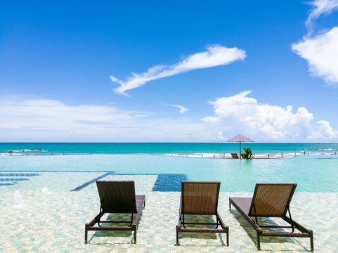 Beach chairs in exotic swimming pool with beautiful seaview and blue sky at Hilton resort Ngapali, Myanmar