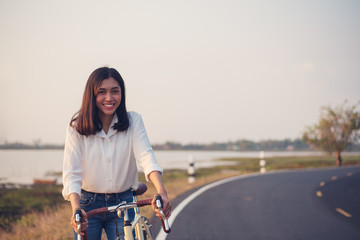 Girl riding touring bicycle in the countryside on the road near the river