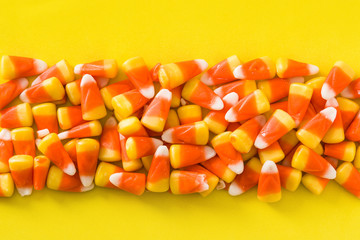 Typical halloween candy corn on yellow background.