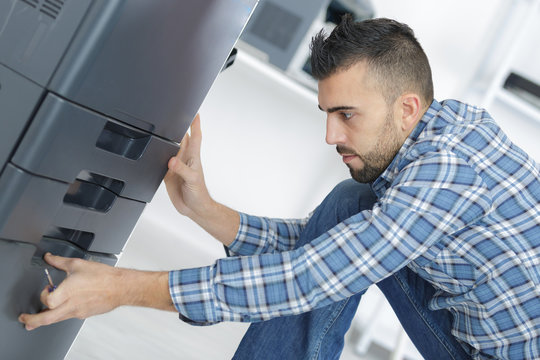 man fixing cartridge in printer machine at office