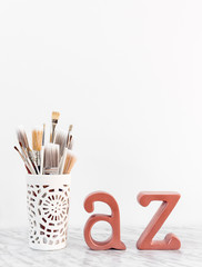 Paintbrushes with metal A and Z letters on marble surface