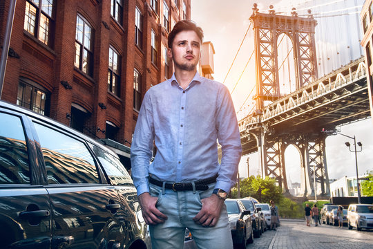 Young adult businessman standing on New York City street wearing smart casual outfit with blue jeans, t-shirt, belt and watch.
