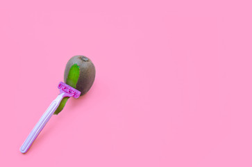 Kiwi fruit and razor on violet background. Hair removal concept.