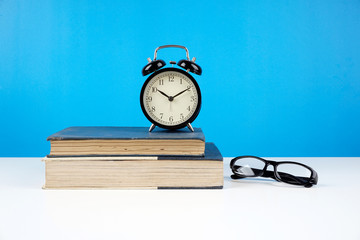 Naklejka premium Education concept. An old book, eyeglasses over blue background