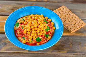 Hummus and tahini with olive oil, pepper, Chickpea, parsley, spices served in a cracker on a rustic wooden table.Hummus Traditional Middle Eastern food.