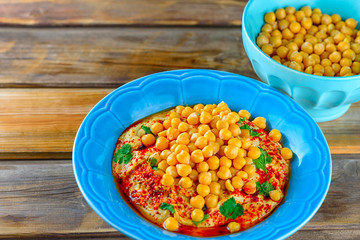 Hummus and tahini with olive oil, pepper, Chickpea, parsley, spices on a rustic wooden table.Hummus Traditional Middle Eastern food commonly served in a pita.