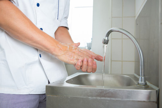 handsome chef washing his hands in commercial kitchen