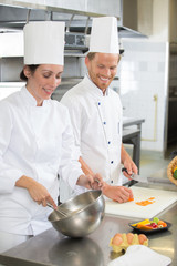 happy chef with beautiful smiling female assistant at kitchen