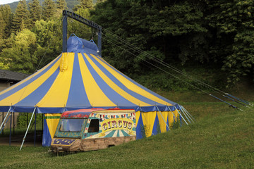 Yellow and blue circus tent near a forest