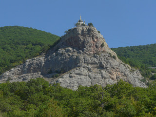 Church with black and gold domes on top of a mountain in the middle of the forest