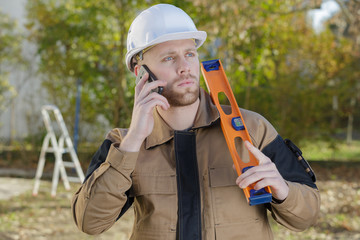 builder standing at a building site talking on mobile-phone