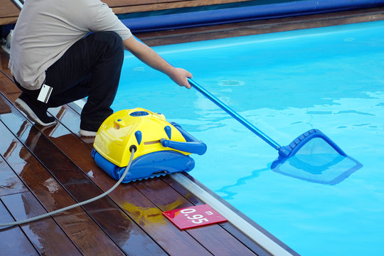Pool cleaner during his work. Cleaning robot for cleaning the botton of swimming pools. Hotel staff worker cleaning the pool.