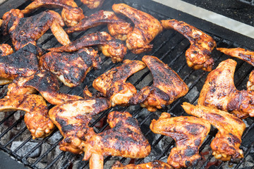 Grilling spicy chicken wings on barbecue grill.