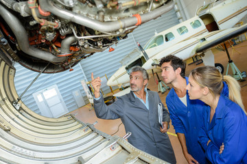airplane engineer showing apprentices mechanics inside undercarriage