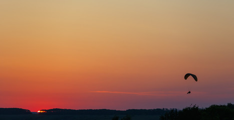 Man flight on a paraglider in a cloudless sky at sunset.