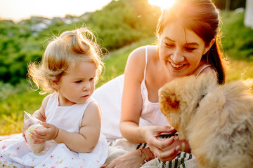 Mother and daughter in park with dog smiling. Sunset. Horizontal photo