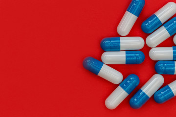 Drugs pills capsules on red background abstract concept