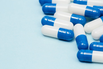 Drugs pills capsules on blue background copy space