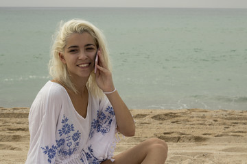 Fototapeta na wymiar Smiling lady talking on the phone on the beach